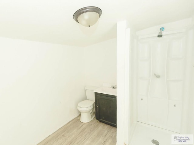 bathroom with hardwood / wood-style flooring, vanity, toilet, and walk in shower