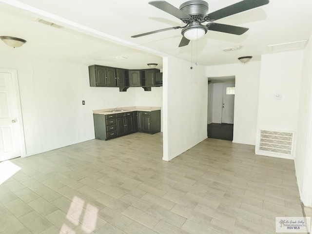 unfurnished living room with ceiling fan, light hardwood / wood-style floors, and sink