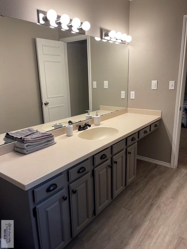 bathroom with wood finished floors, vanity, and baseboards