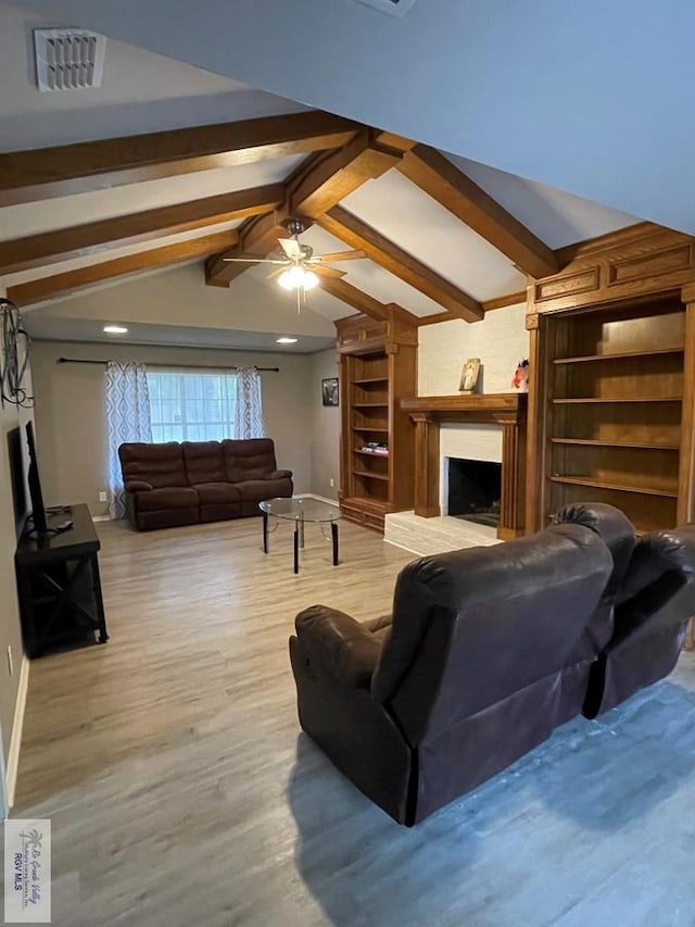 living area with a fireplace with raised hearth, wood finished floors, visible vents, and vaulted ceiling with beams