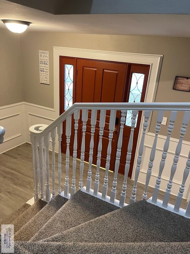 interior space featuring wainscoting, wood finished floors, and a decorative wall