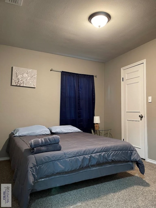 carpeted bedroom with visible vents, a textured ceiling, and baseboards