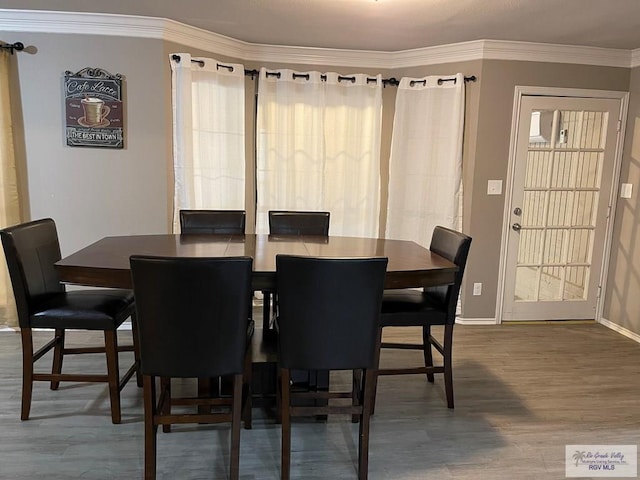 dining room featuring ornamental molding, wood finished floors, and baseboards