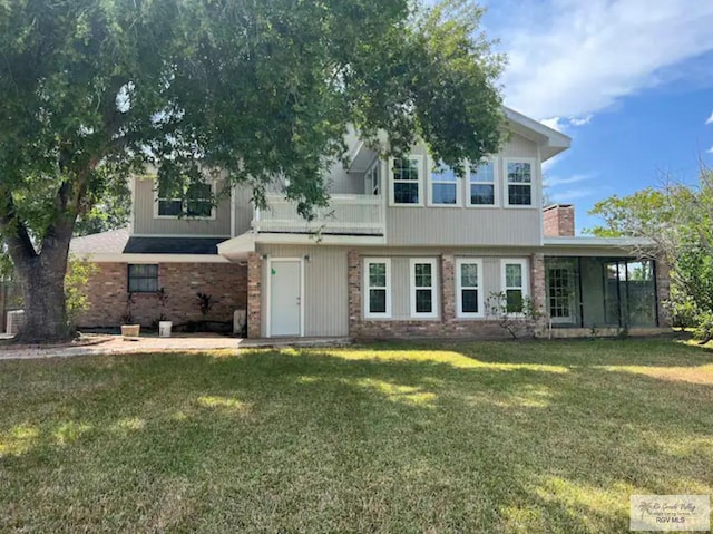 view of front of house featuring a balcony, brick siding, and a front yard