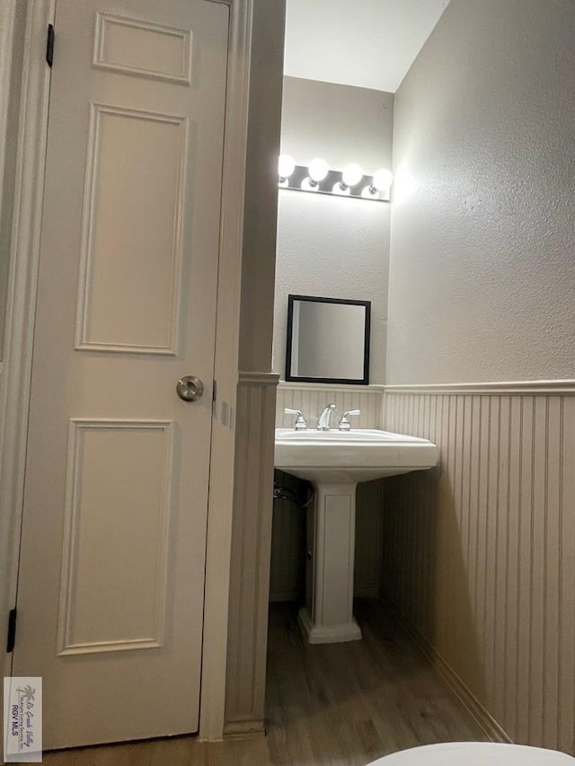 bathroom with a wainscoted wall and wood finished floors