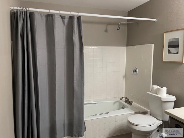 bathroom with a textured wall, tiled shower / bath combo, vanity, and toilet