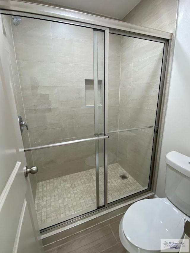 bathroom with toilet and a shower with door