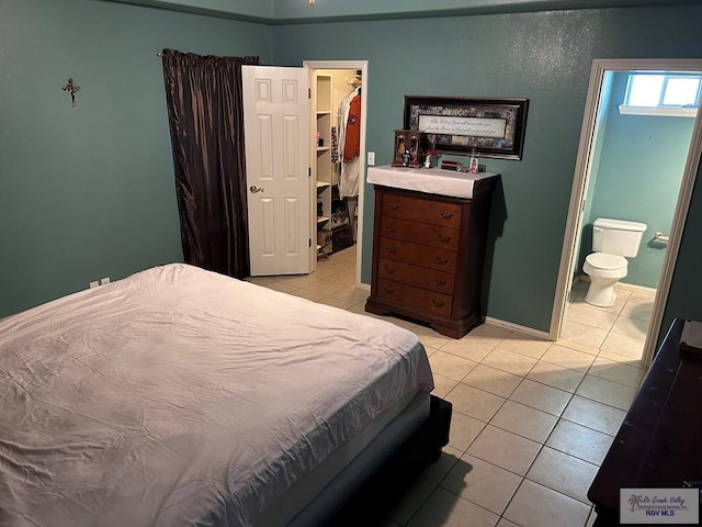 tiled bedroom featuring ensuite bathroom, a spacious closet, and a closet