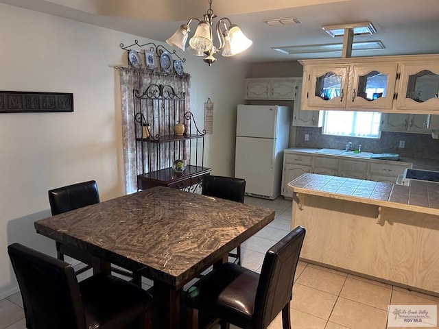 tiled dining room featuring sink and a chandelier