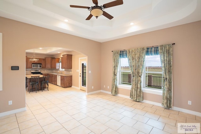 interior space featuring a raised ceiling and ceiling fan