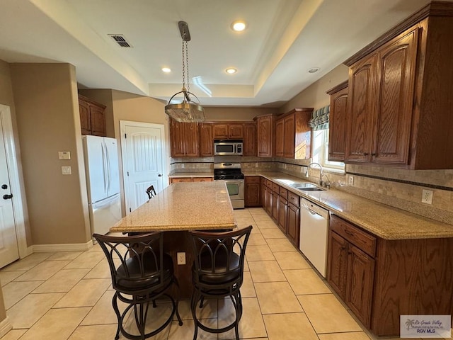 kitchen featuring backsplash, sink, appliances with stainless steel finishes, decorative light fixtures, and a kitchen island