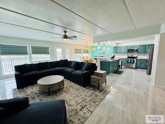 living room with a textured ceiling, ceiling fan, and sink