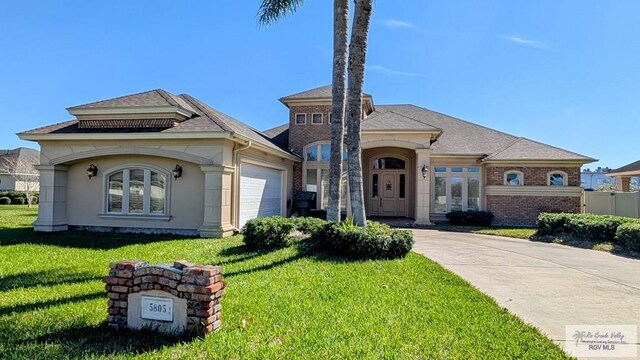 5805 Acacia, Harlingen, TX 78552 - view of front facade with stucco siding, driveway, a front yard, and an attached garage