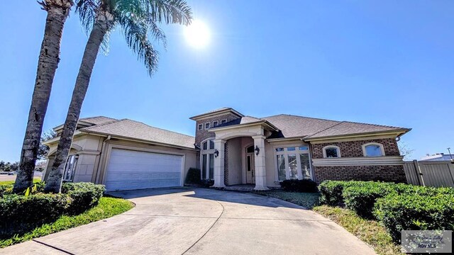 5805 Acacia, Harlingen, TX 78552 - view of front of home featuring brick siding, a garage, driveway, and roof with shingles