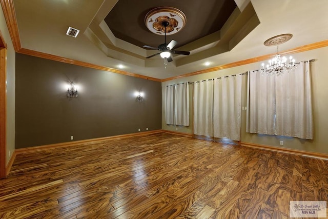 spare room featuring wood-type flooring, ceiling fan with notable chandelier, a tray ceiling, and ornamental molding