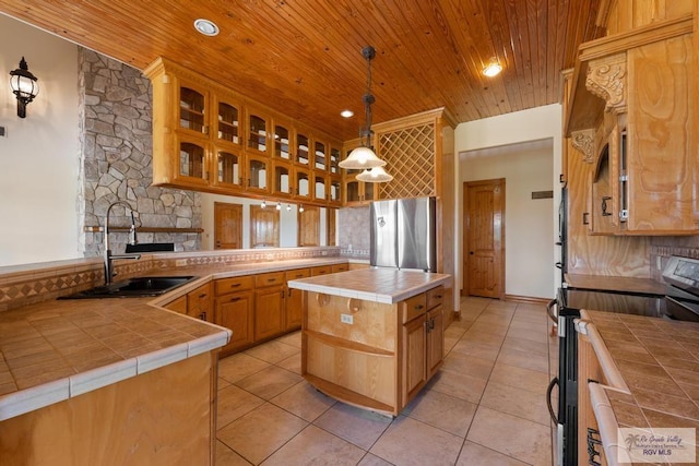 kitchen featuring decorative light fixtures, black range with electric cooktop, tile counters, a kitchen island, and stainless steel refrigerator