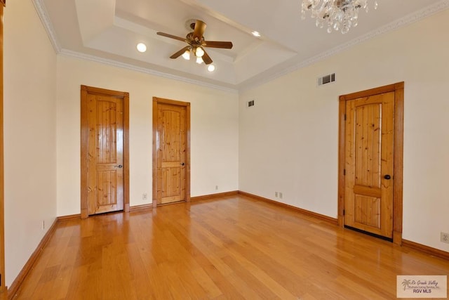 unfurnished bedroom featuring hardwood / wood-style floors, a tray ceiling, and ornamental molding