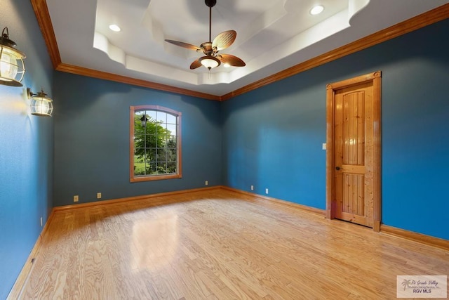 empty room with ceiling fan, light hardwood / wood-style floors, ornamental molding, and a tray ceiling