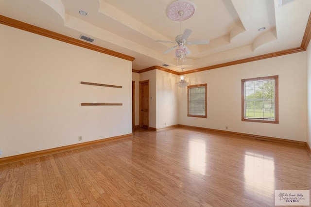 empty room featuring a tray ceiling, crown molding, ceiling fan, and light hardwood / wood-style floors