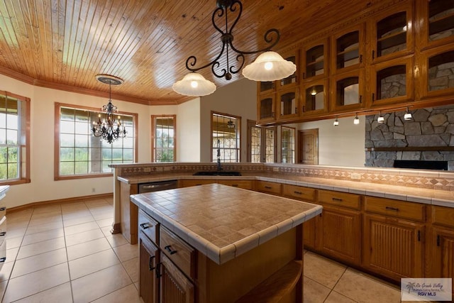 kitchen with tile countertops, a kitchen island, hanging light fixtures, and a wealth of natural light