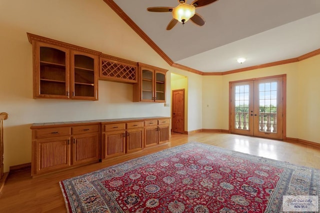 kitchen featuring vaulted ceiling, light wood-type flooring, ornamental molding, and french doors