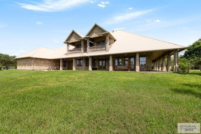 back of property with a lawn and a balcony