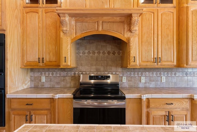 kitchen featuring stainless steel range with electric stovetop, tile counters, and decorative backsplash