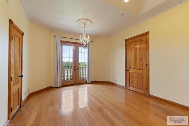 empty room with a notable chandelier, french doors, crown molding, and light hardwood / wood-style flooring