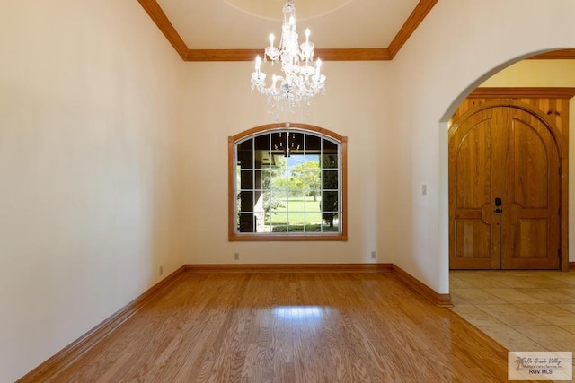 unfurnished room featuring a chandelier, light hardwood / wood-style floors, and ornamental molding