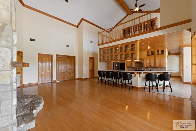 living room with ceiling fan, beam ceiling, high vaulted ceiling, a fireplace, and light hardwood / wood-style floors