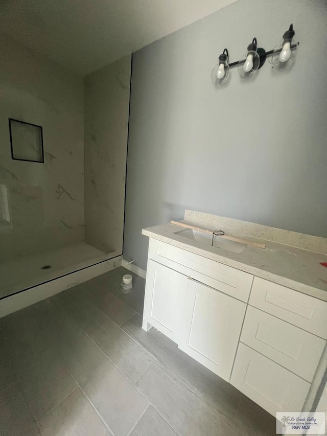 full bathroom with a marble finish shower, tile patterned flooring, and vanity