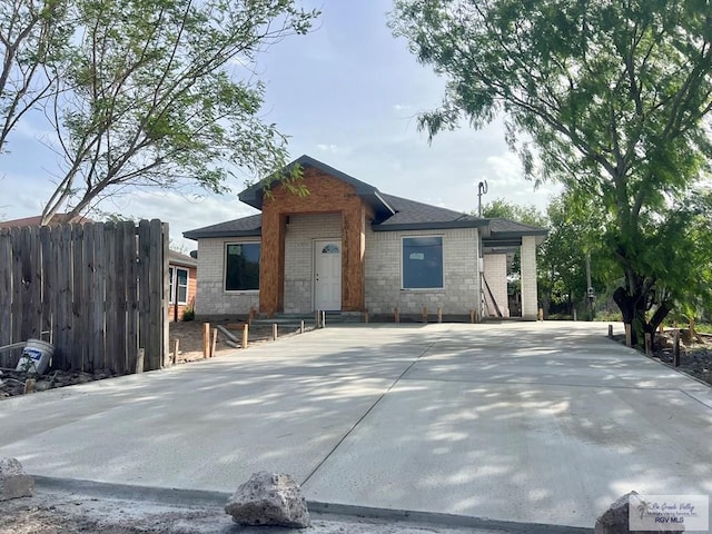 view of front of home featuring brick siding, fence, and stone siding