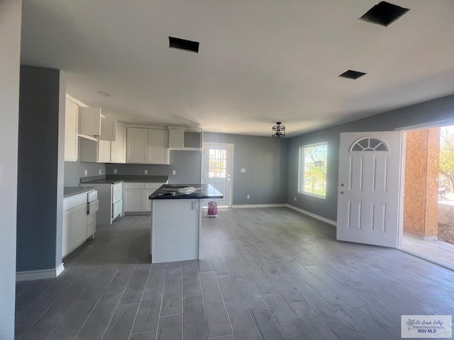 kitchen with a kitchen island, baseboards, open floor plan, dark wood-type flooring, and white cabinets
