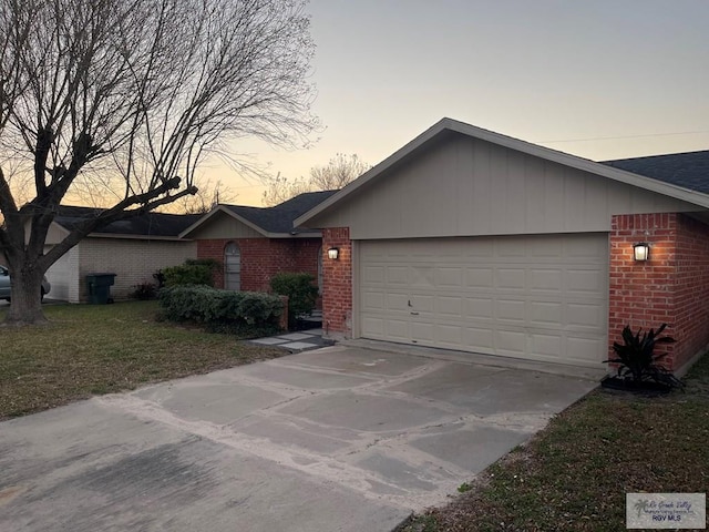 ranch-style home featuring a garage and a lawn