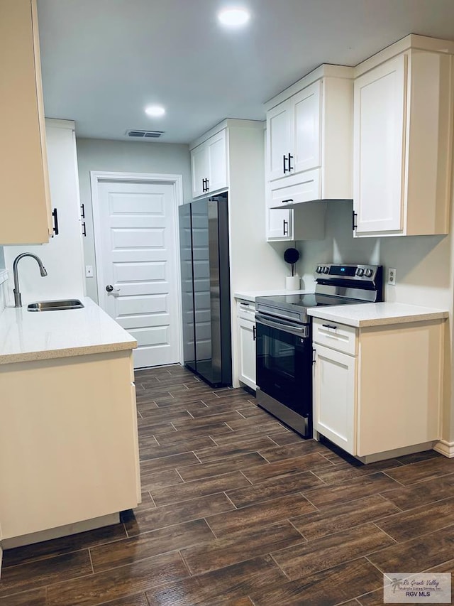 917 S Houston Dr, Harlingen, TX 78550 - kitchen with visible vents, wood finish floors, stainless steel range with electric stovetop, freestanding refrigerator, and a sink