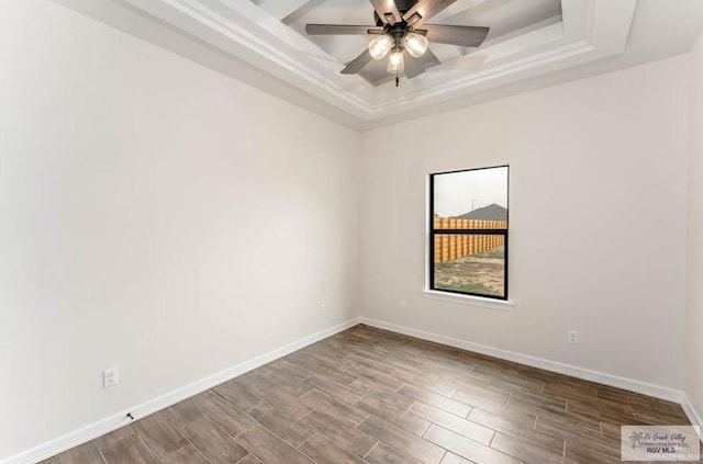 empty room with hardwood / wood-style flooring, ceiling fan, and a tray ceiling