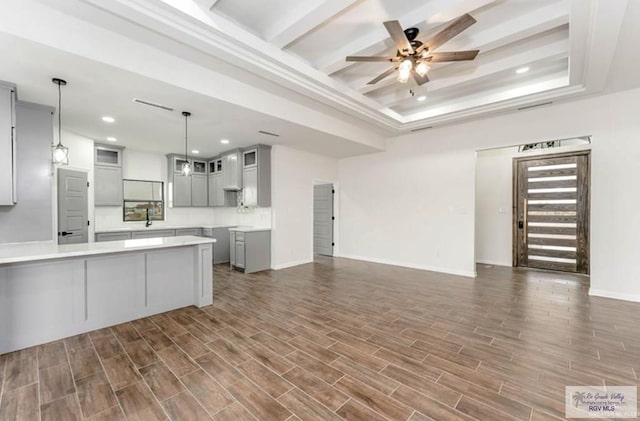 kitchen with gray cabinetry, ceiling fan, a raised ceiling, dark hardwood / wood-style floors, and decorative light fixtures