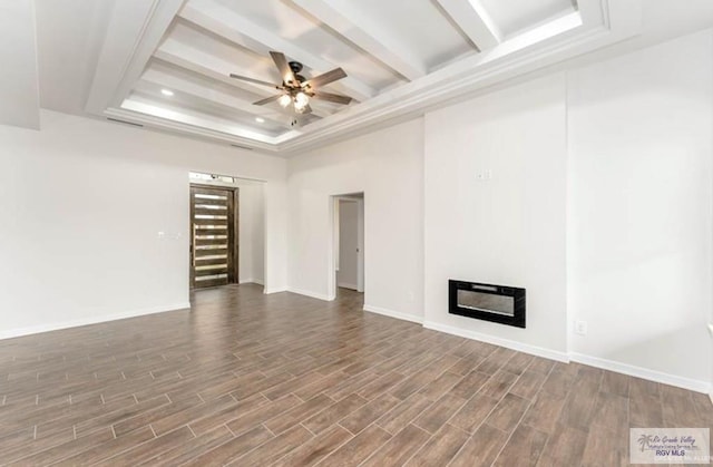 unfurnished living room with a raised ceiling, ceiling fan, and dark hardwood / wood-style floors