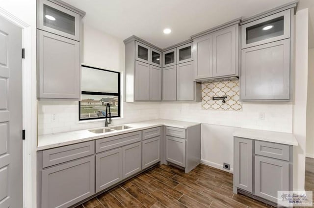 kitchen with gray cabinetry, backsplash, dark wood-type flooring, and sink