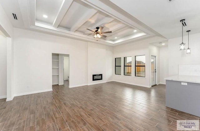 unfurnished living room with a raised ceiling, ceiling fan, and dark hardwood / wood-style flooring