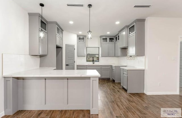 kitchen with gray cabinetry, pendant lighting, sink, dark hardwood / wood-style floors, and kitchen peninsula