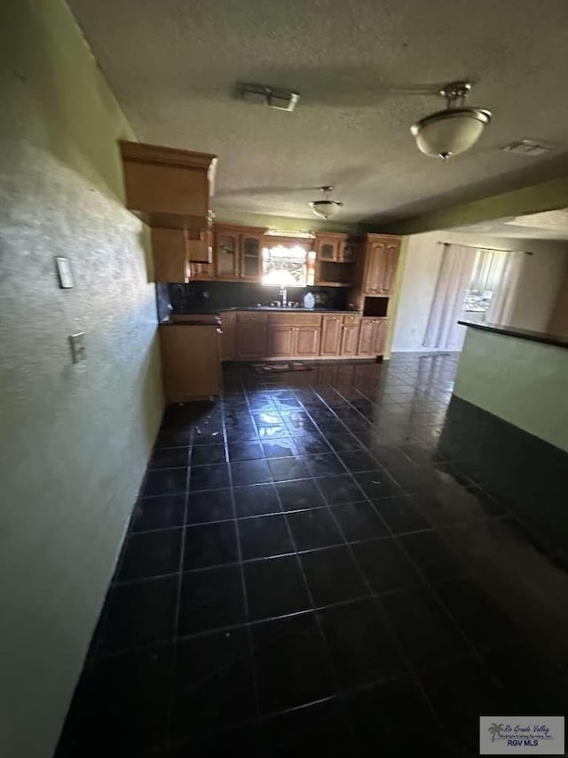 kitchen with a textured ceiling, dark tile patterned floors, and sink