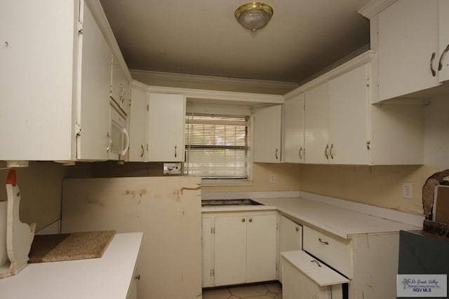 825 E Vinson Ave, Harlingen, TX 78550 - kitchen featuring ornamental molding, light countertops, white cabinetry, stovetop, and white microwave