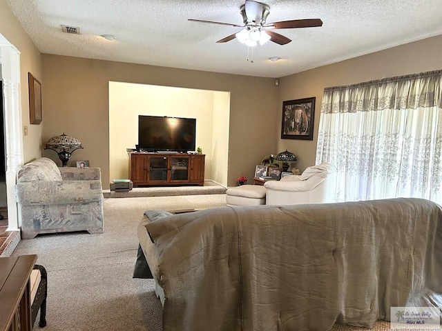 carpeted living room with a textured ceiling and ceiling fan