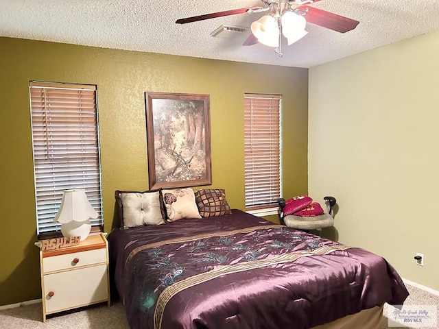 bedroom with a textured ceiling, light colored carpet, and ceiling fan