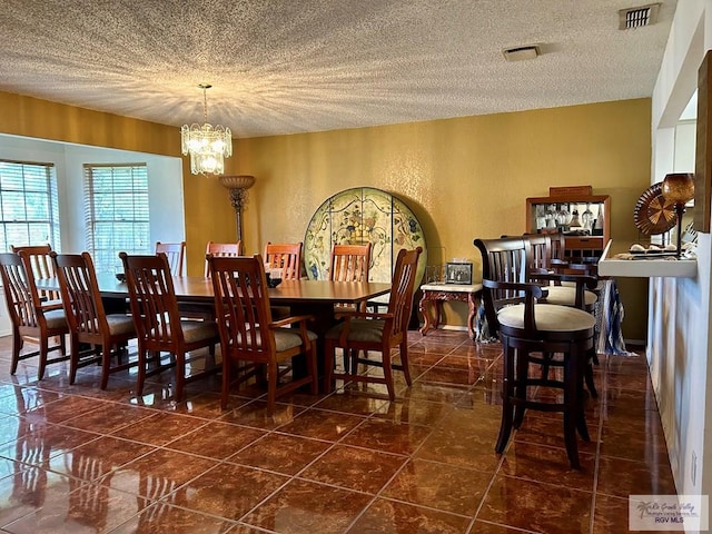 dining space featuring a textured ceiling, dark tile patterned flooring, and a notable chandelier