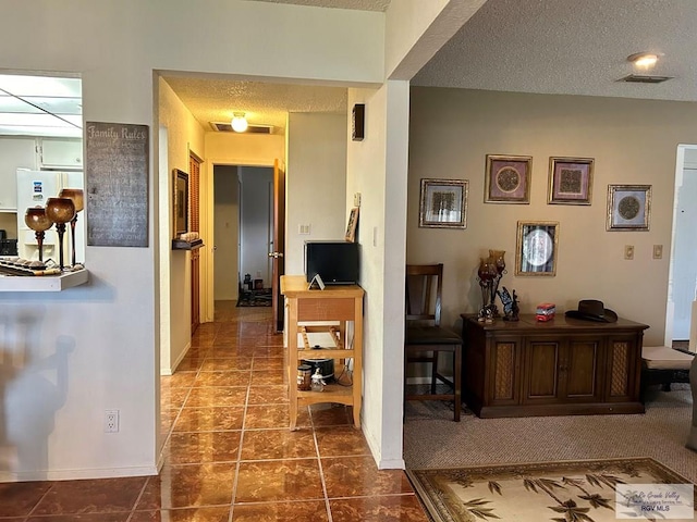 hallway featuring dark tile patterned floors and a textured ceiling