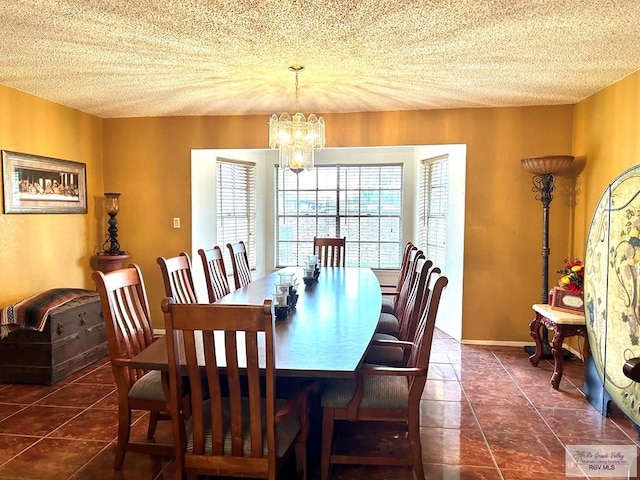 dining area with a chandelier, a textured ceiling, and dark tile patterned flooring