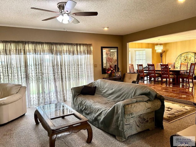 living room featuring a textured ceiling, carpet floors, and ceiling fan with notable chandelier