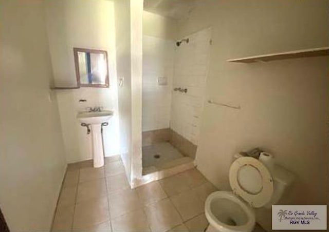 bathroom featuring tile patterned floors, toilet, and a shower stall